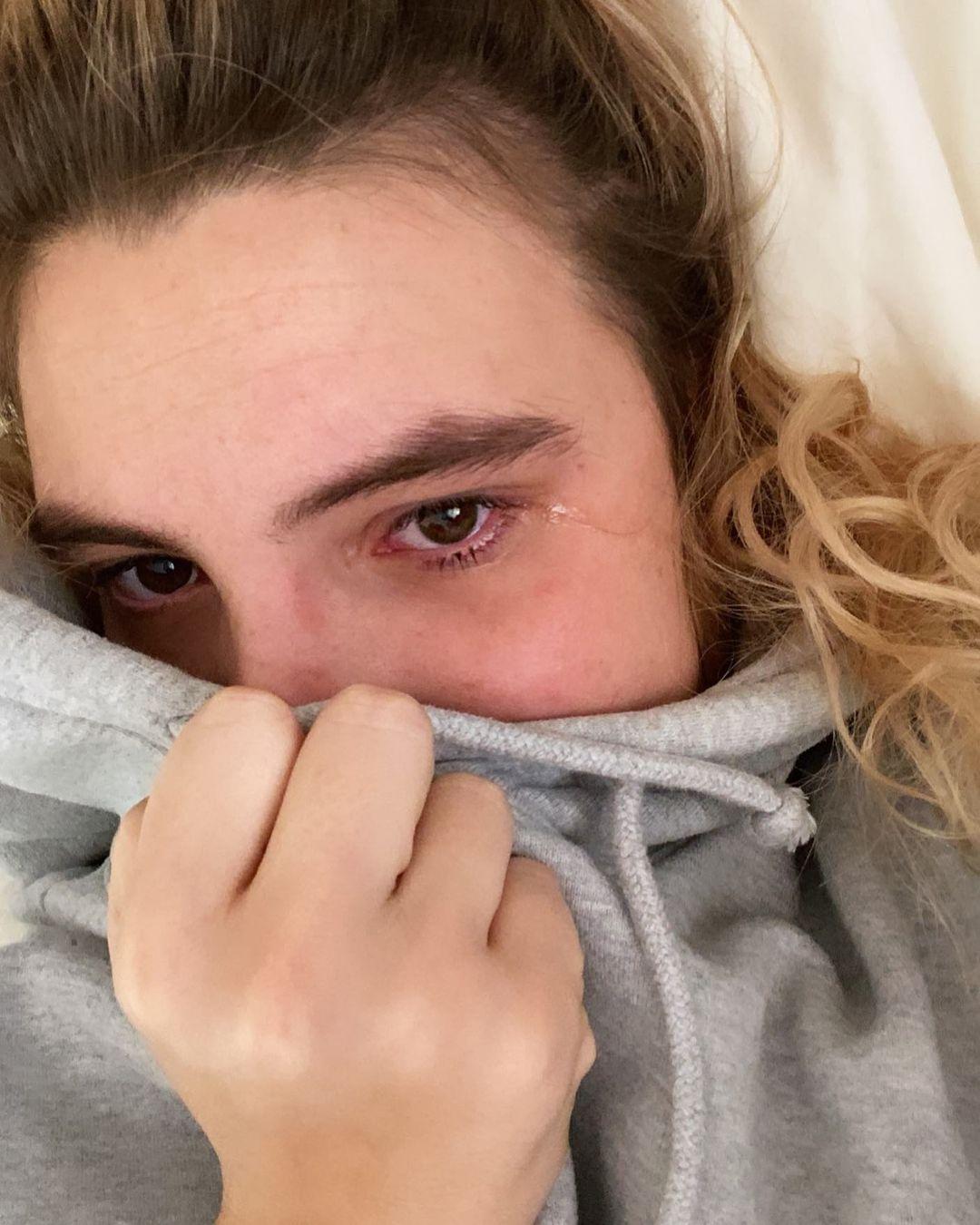 Lele Pons wrapped in a gray blanket, looking at the camera with a contemplative expression