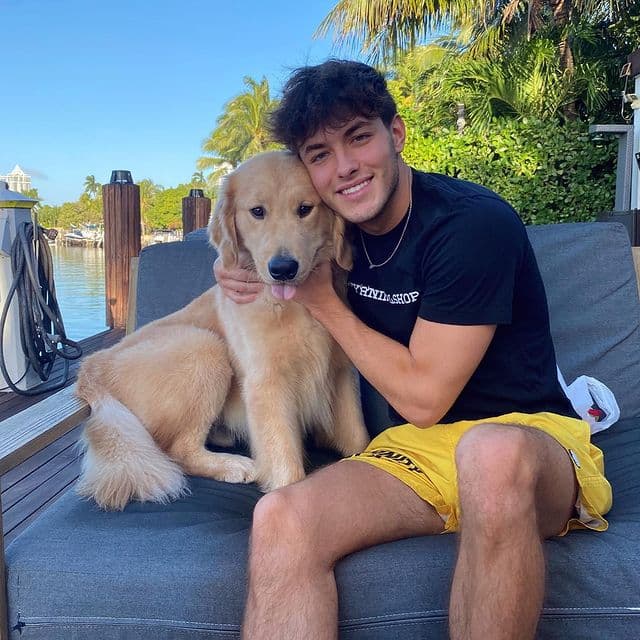 Griffin Johnson poses with a golden retriever on a waterfront dock
