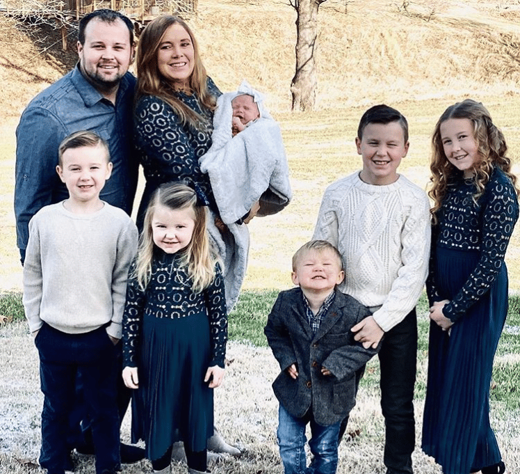 Josh Duggar with wife and children posing outdoors against a brick wall