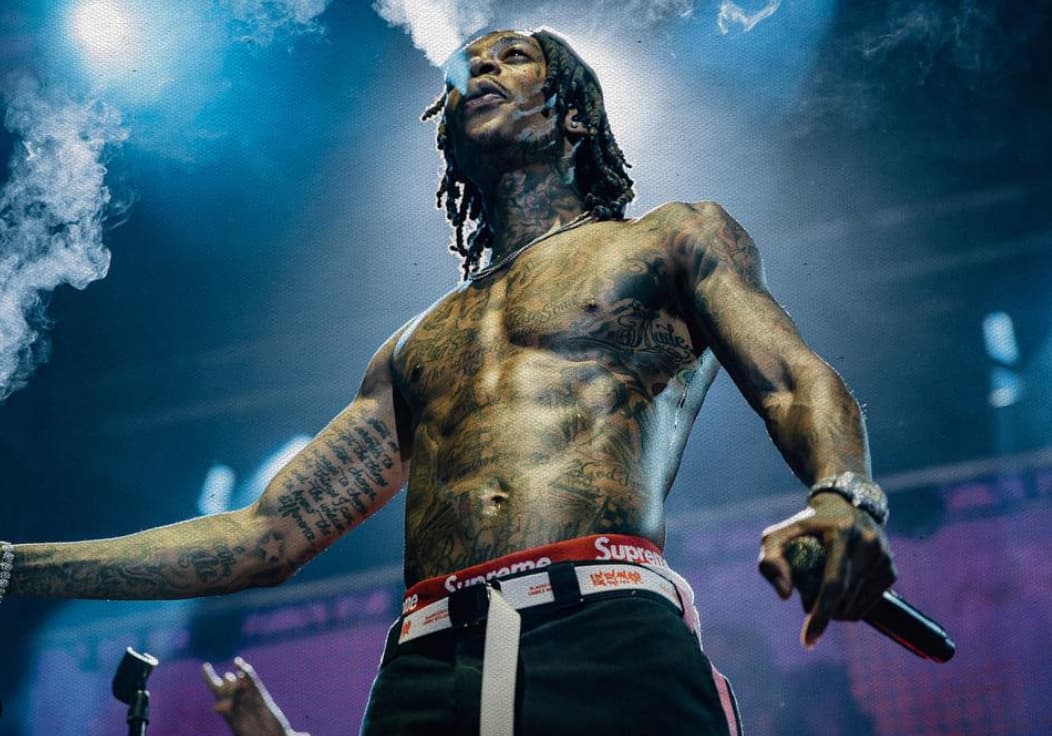 Wiz Khalifa performing shirtless on stage with microphone