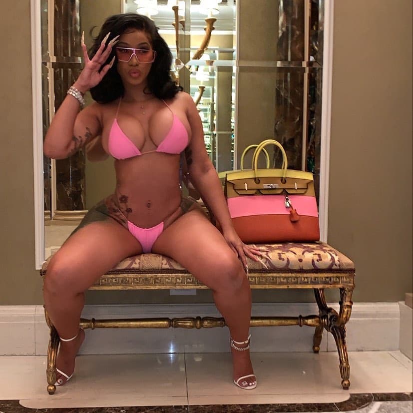 Woman in pink bikini sitting on ornate bench in luxury bathroom