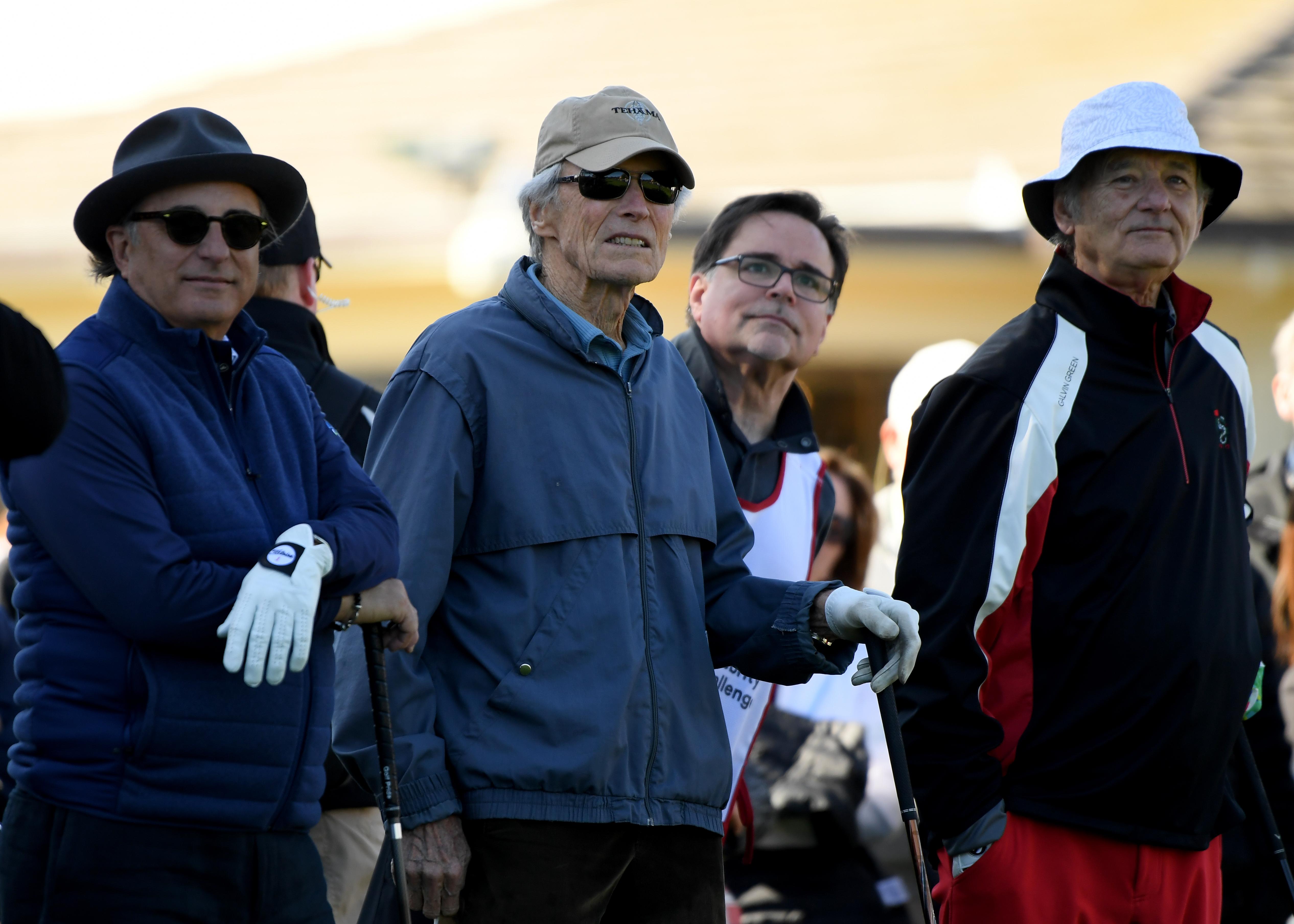 Four men in winter clothing and hats standing together at a ski resort
