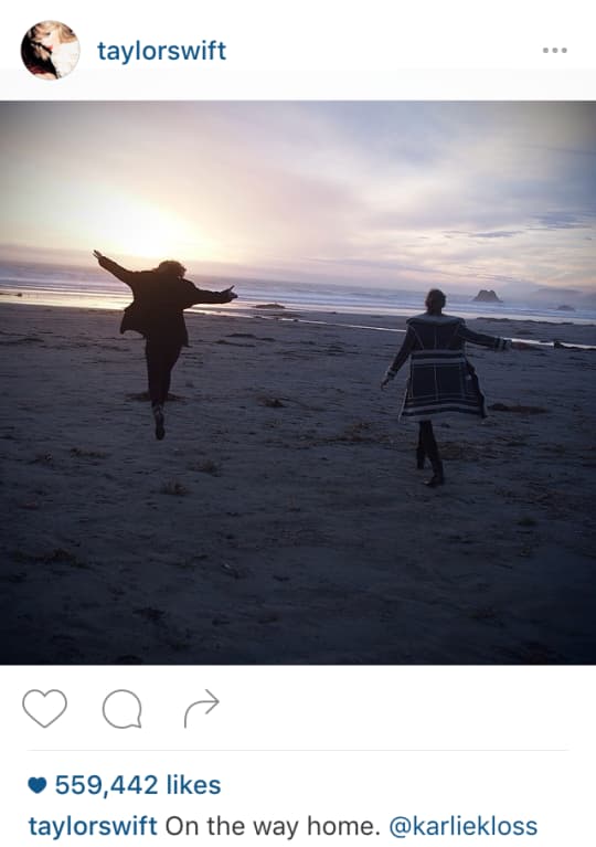 Two people running on a beach at sunset with ocean and rocks in background