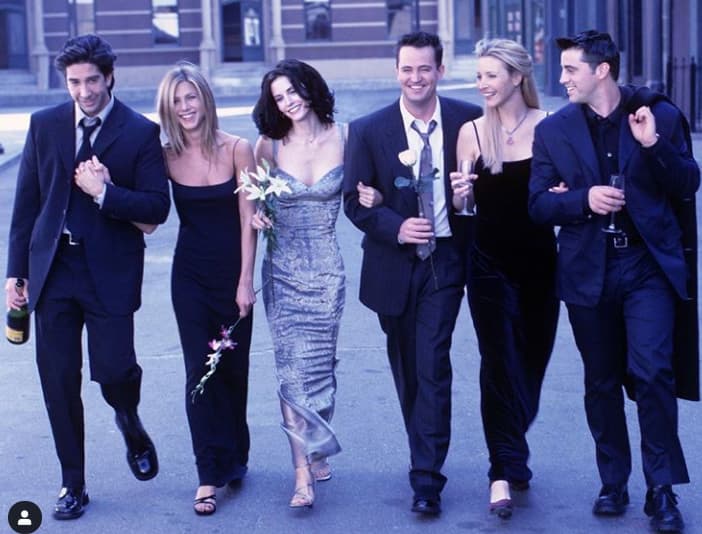 Six people in formal attire walking together outdoors at night