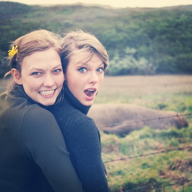 Two women posing together outdoors with mountains and water in the background