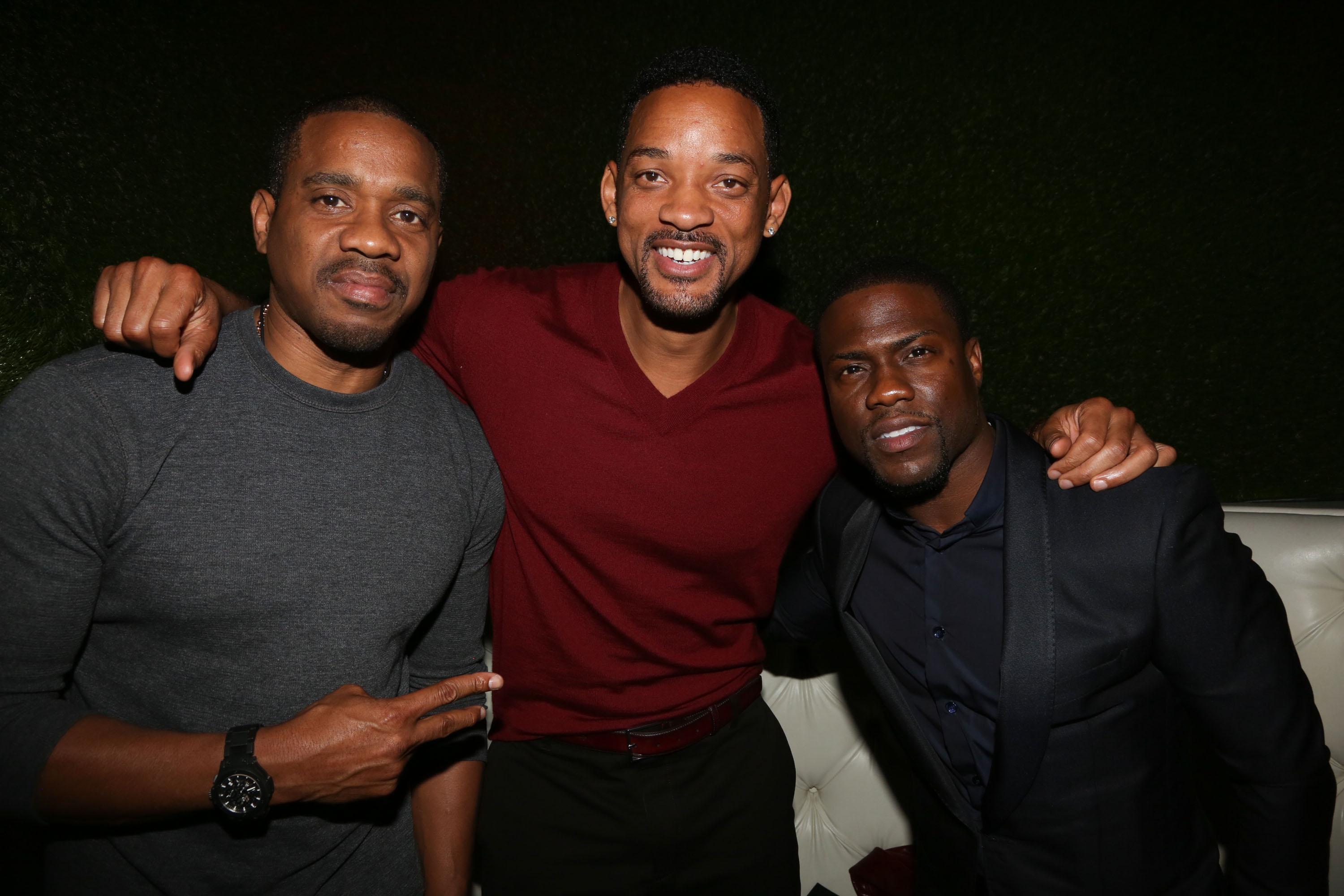 Four men posing together at an indoor event with a dark background.