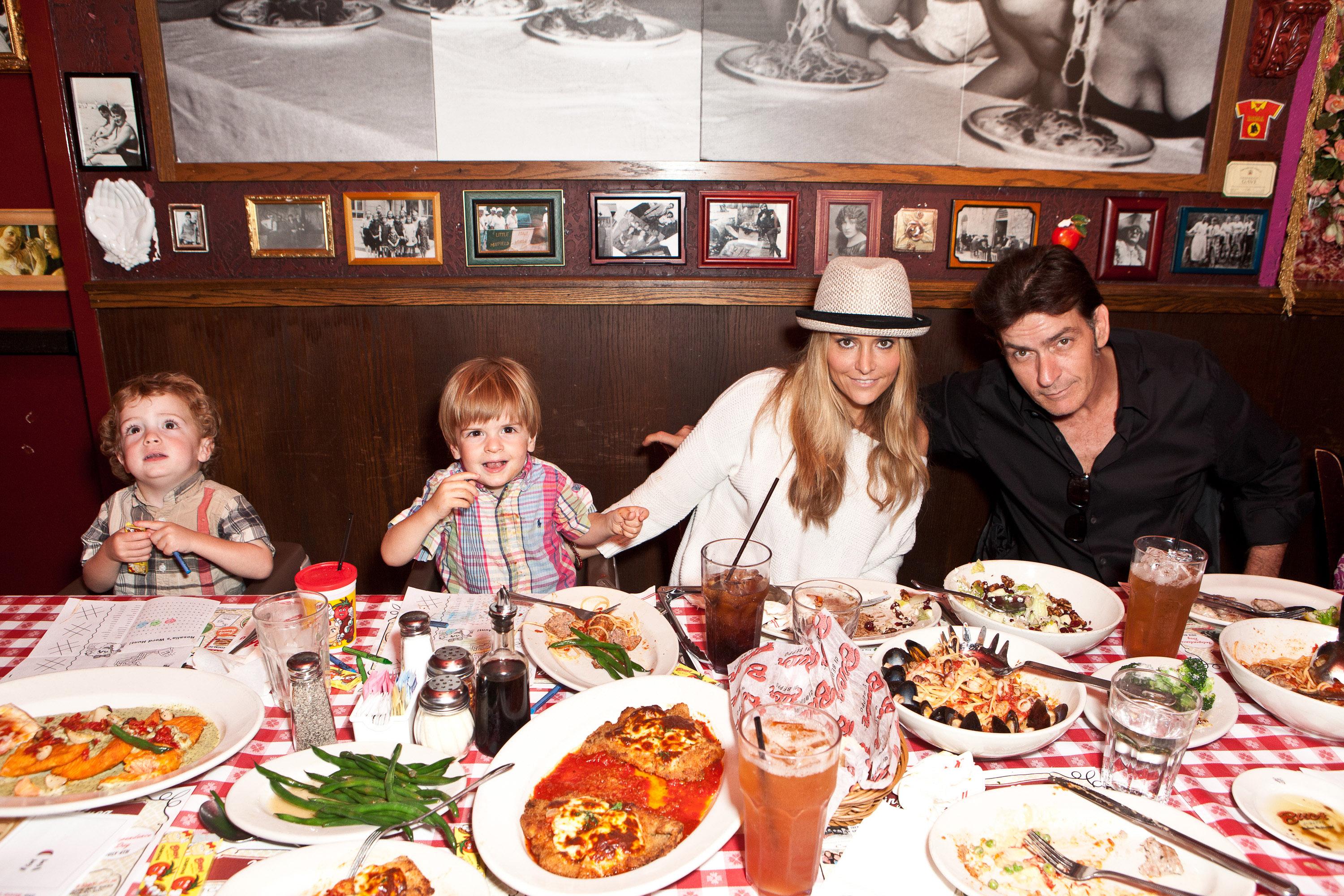 Family dining together at a restaurant table with various dishes and beverages
