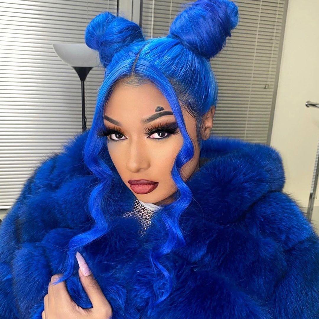 Woman with bright blue wavy hair and dual buns wearing a blue fur coat