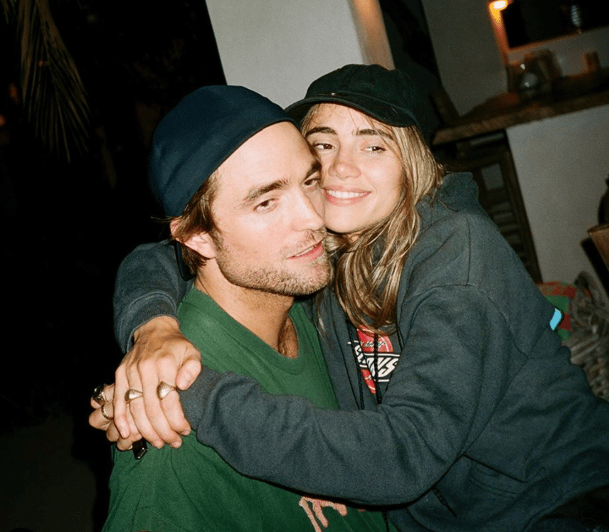 Robert Pattinson and Suki Waterhouse posing together at an indoor event