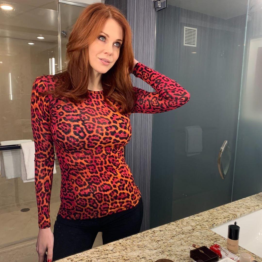 Maitland Ward poses in a bathroom mirror wearing a red leopard print top